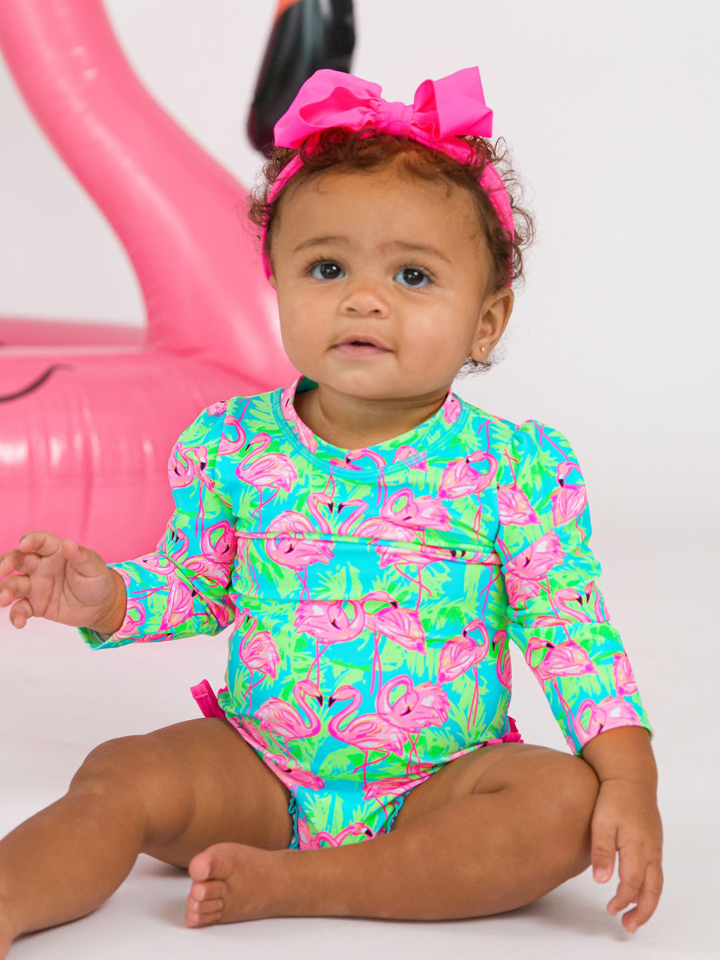 RuffleButts Baby Girls UPF 50+ Sun Protection Tropical Print Long Sleeve One Piece Rash Guard Swimsuit with Zipper - Neon Flamingo Fun, 12-18m